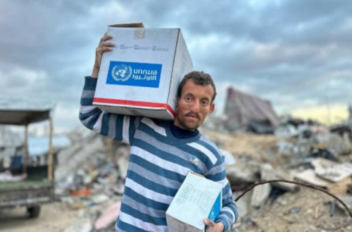 Palestiniano em Gaza com caixote de ajuda da UNRWA